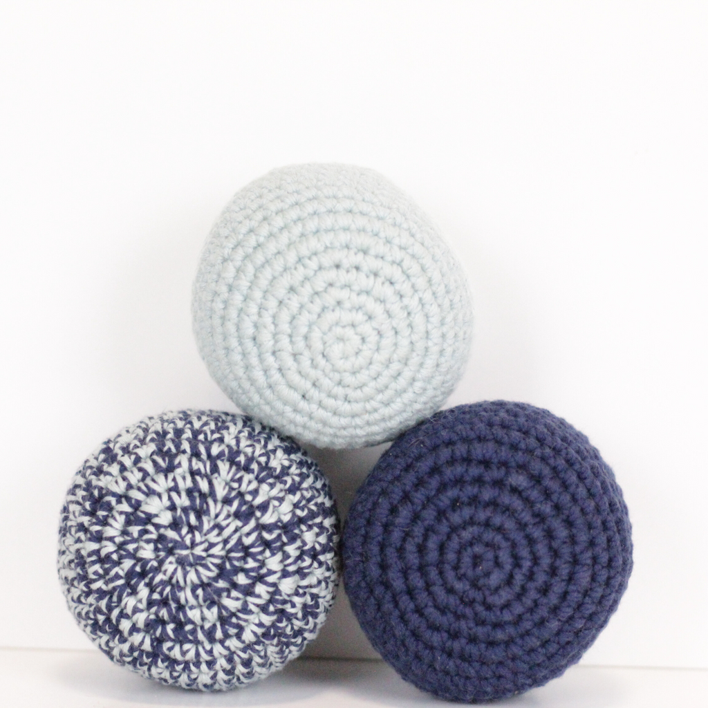 Three crocheted balls in merle blue, baby blue, and navy. Handmade crochet dog toys from Lana Royals Pet Wear.