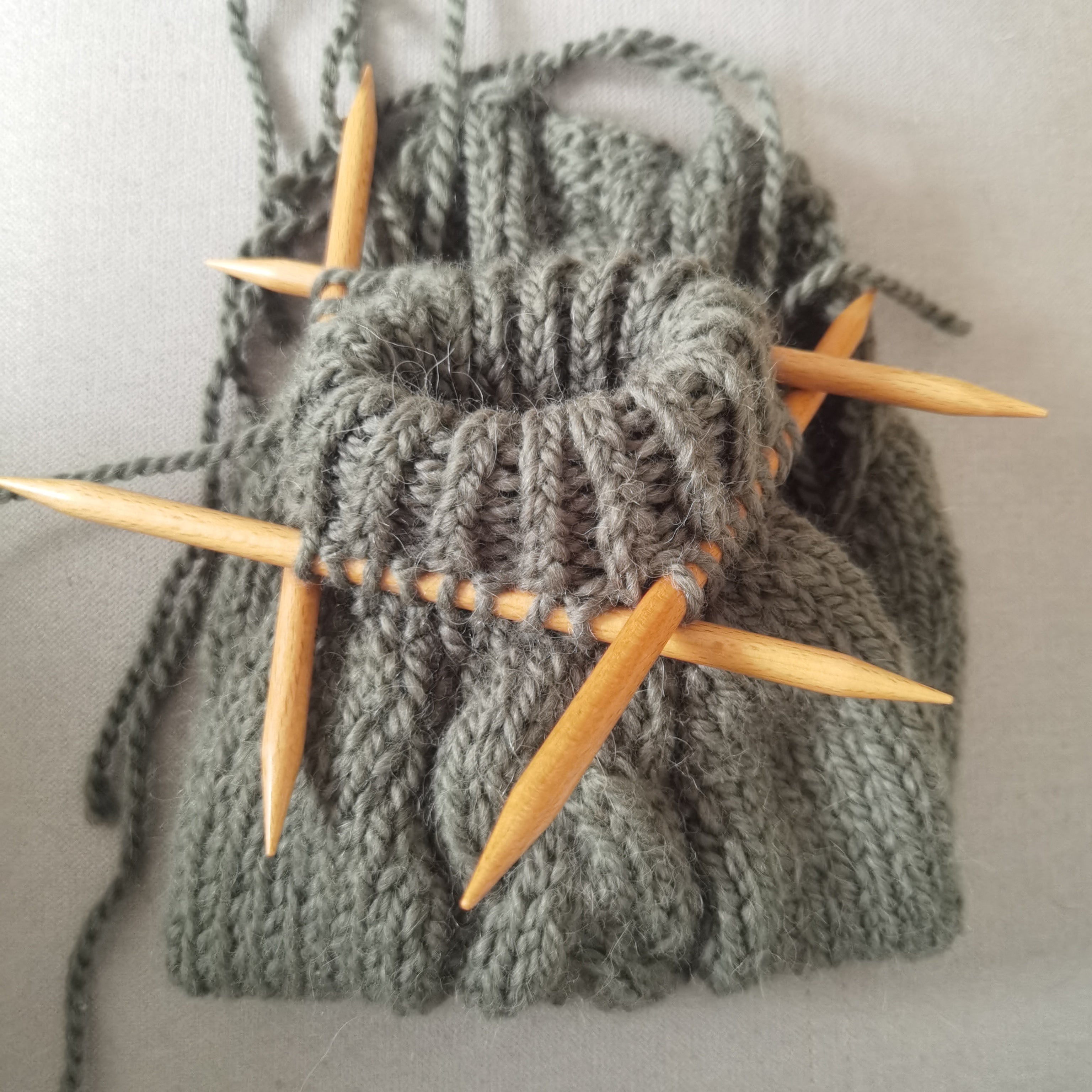 Moss green handmade knitted dog sweater with wooden knitting needles, from Lana Royals Pet Wear.