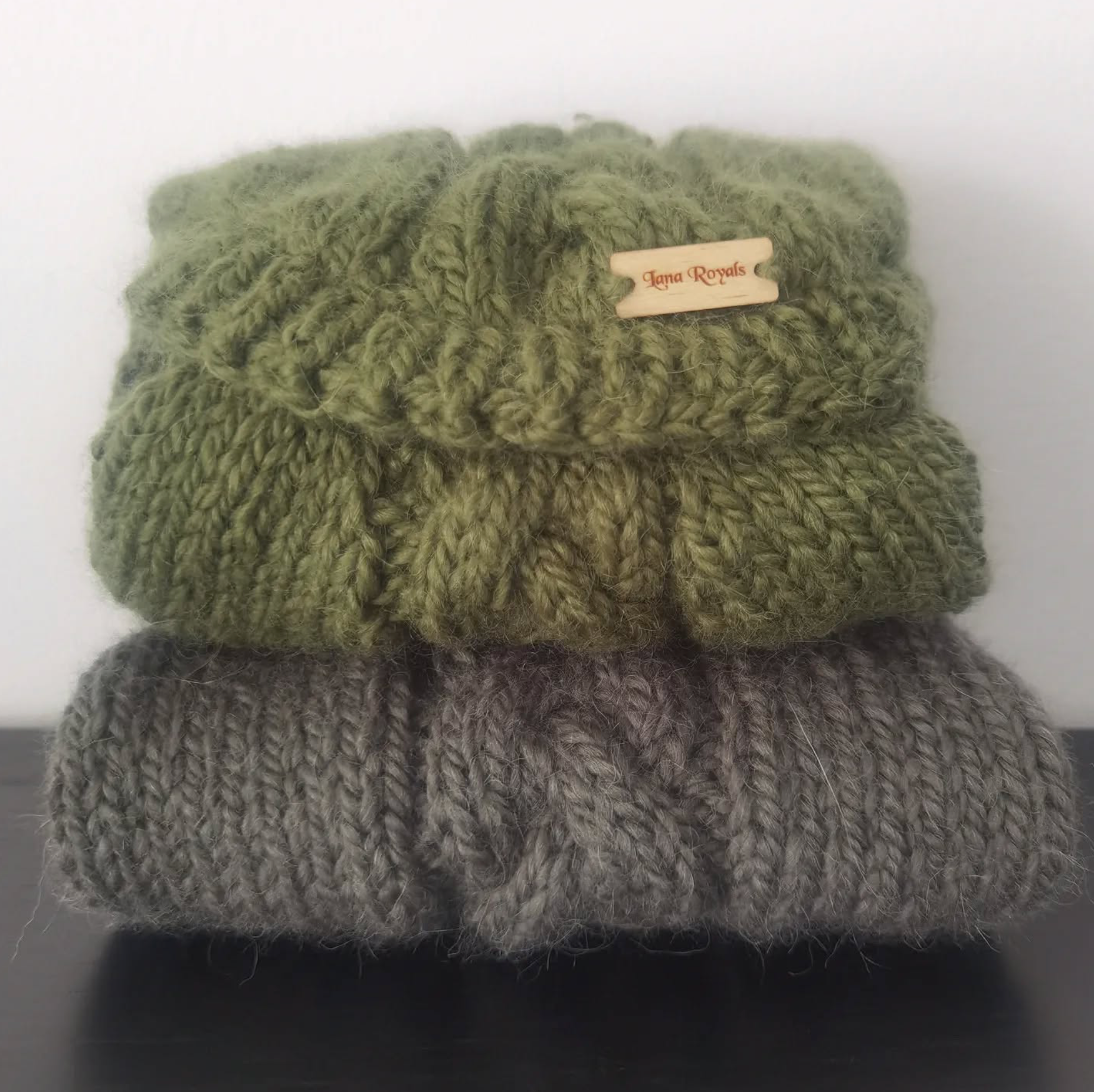 Stack of forest green and moss green handmade knitted sweaters with a brand tag for Lana Royals Pet Wear, custom made to measure dog and cat clothing.