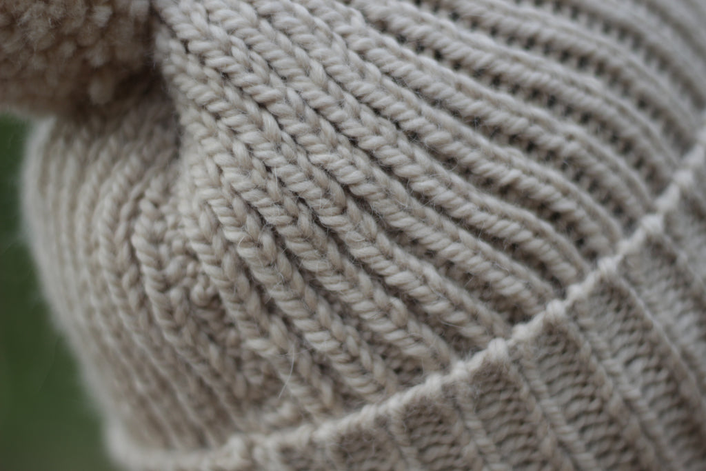Close-up of beige alpaca wool knitted fabric with a textured ribber pattern. Handmade by Lana Royals Pet Wear Store.